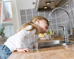 Girl drinking water at kitchen sink